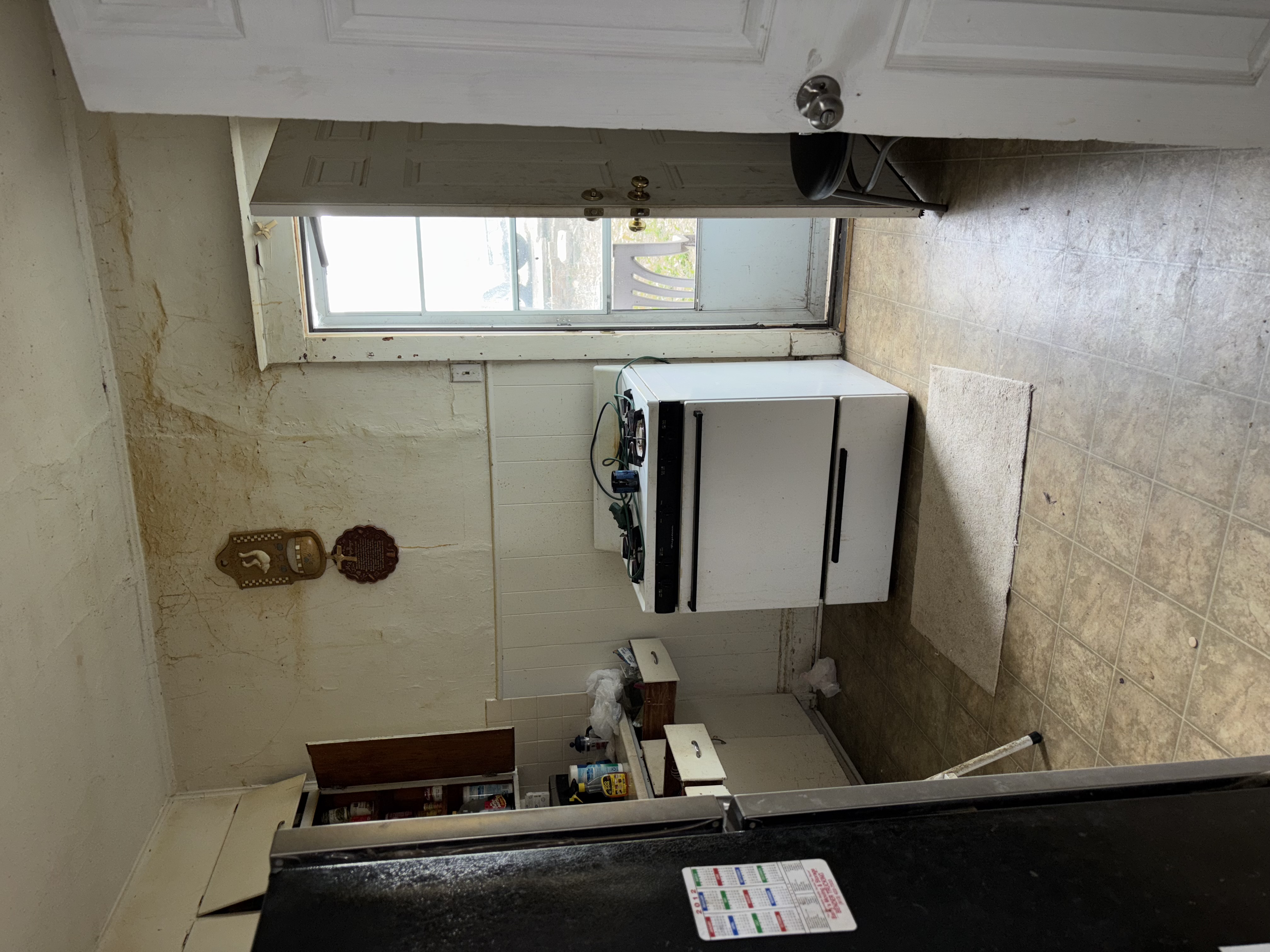 Kitchen before renovation - damaged cabinets and walls