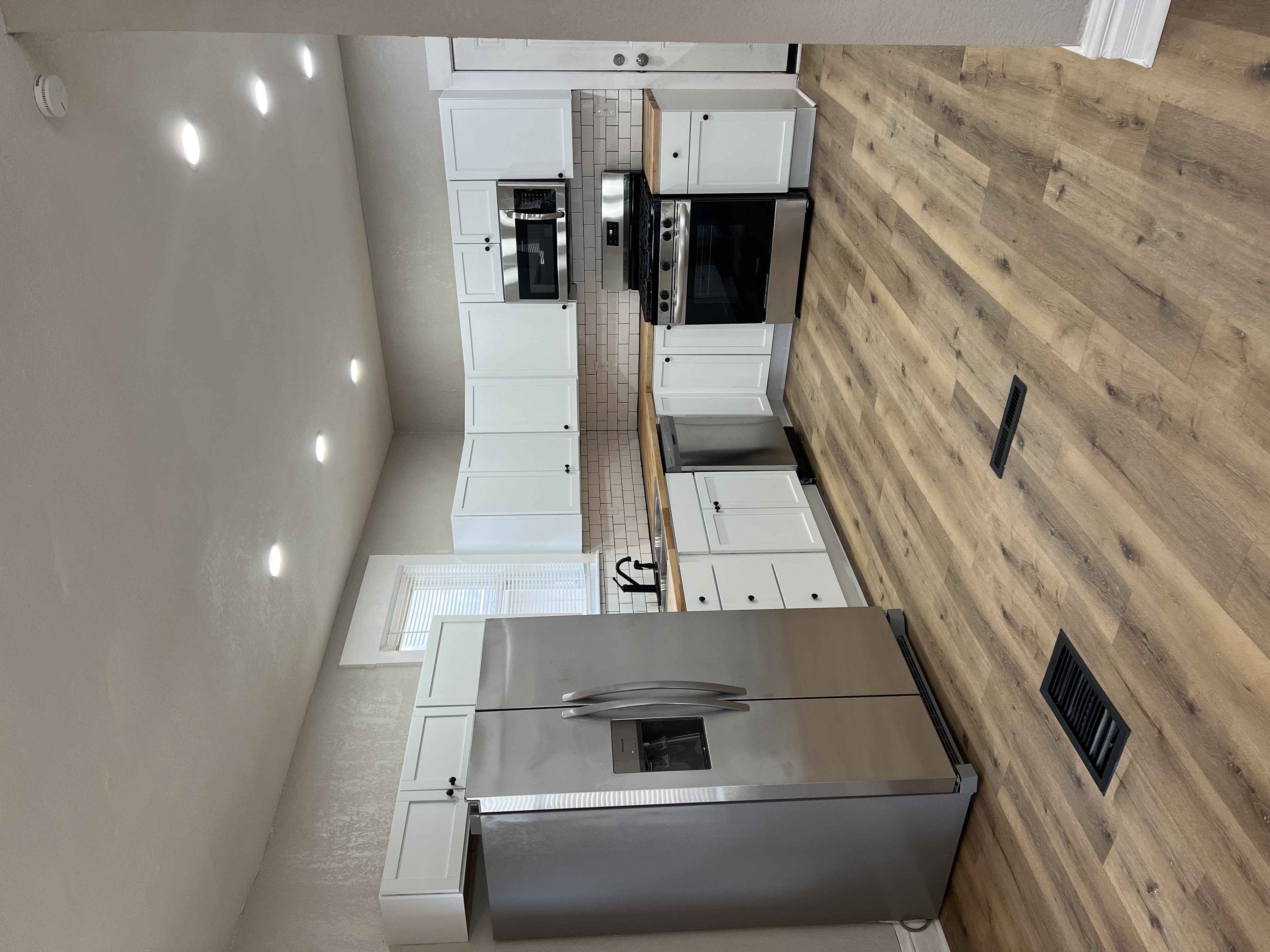Kitchen after renovation - white shaker cabinets, subway tile, stainless appliances
